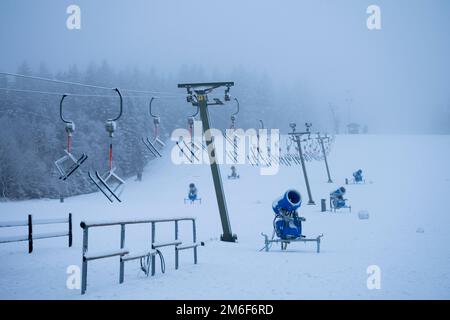 Telesilla con cañones de nieve en una pista de esquí nevada Foto de stock