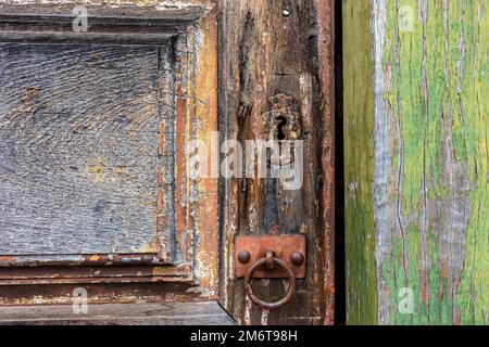 Antigua puerta de madera y cerradura deteriorada por el tiempo y el óxido en una casa de estilo colonial Foto de stock