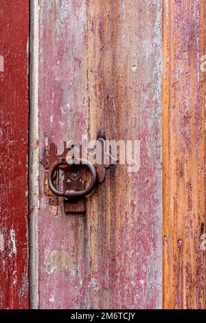 Antigua puerta de madera colorida y cerradura deteriorada por el tiempo y el óxido en una casa colonial Foto de stock