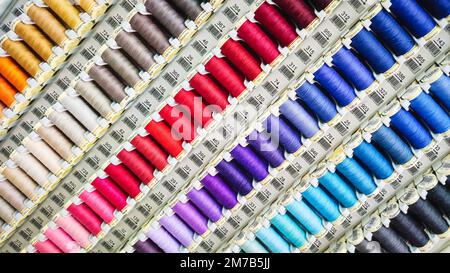 Carretes de hilos de diferentes colores en exhibición en una tienda de costura y artesanía Foto de stock