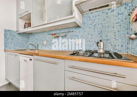 una cocina con paredes azules y armarios blancos en la pared, hay un  televisor montado sobre el fregadero Fotografía de stock - Alamy