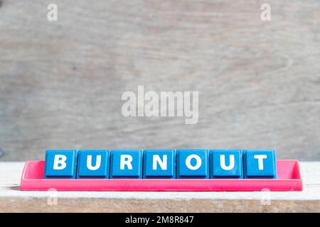 Letra del alfabeto del azulejo con la palabra burnout en el estante del color rojo sobre fondo de madera Foto de stock