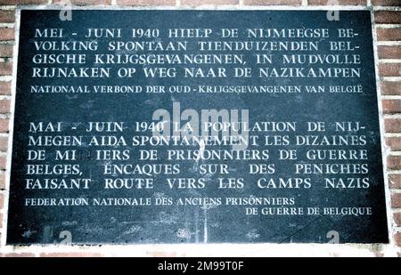 La inscripción en la placa es 'En mayo-junio de 1940, los ciudadanos de Nijmegen ofrecieron espontáneamente ayuda a decenas de miles de prisioneros de guerra belgas en su camino a los campos nazis en las estrechas barcazas del Rin'. Fue erigido el 16 de mayo de 1992 por la Federación Nacional Belga de ex Prisioneros de Guerra. Entre el 30th de mayo y el 5th de junio, noventa barcazas, repletas de un cuarto de millón de prisioneros de guerra belgas, fueron amarradas en el muelle de Waal. El puente de la carretera había sido soplado por los holandeses el 10th de mayo y estaba en el agua, bloqueando su camino a los campos de Alemania. Ciudadanos de los distritos circundantes de N Foto de stock