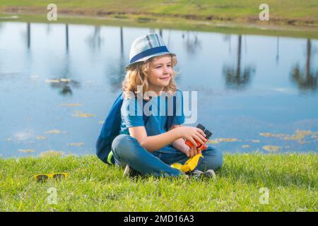 Lindo niño rubio con binoculares llevando sombrero explorer y mochila en la  naturaleza. Niño explorador senderismo y aventura Fotografía de stock -  Alamy