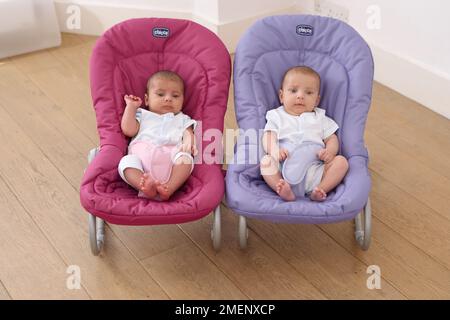Bebé y niña gemelos sentados en sillas hinchables, vista frontal, 11 semanas