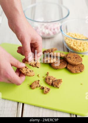 Romper las galletas con chispas de chocolate en trozos pequeños, haciendo yogur congelado Foto de stock