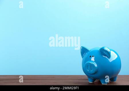 Piggy bank en la mesa de madera contra el fondo azul claro. Espacio para texto Foto de stock