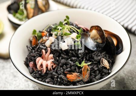 Delicioso risotto negro con mariscos en un tazón en la mesa Foto de stock