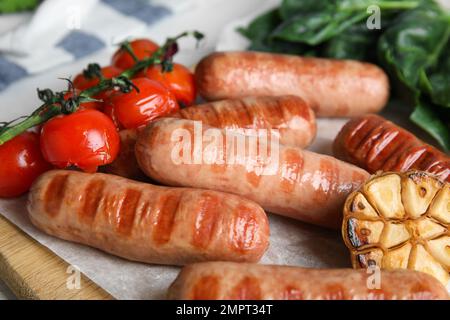 Deliciosas salchichas a la parrilla con verduras servidas en la mesa Foto de stock