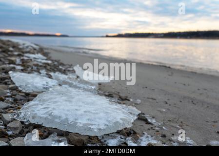 Pequeños témpanos de hielo del primer hielo se encuentran en la orilla arenosa cerca del agua del río Vilyui en Yakutia al amanecer del día Foto de stock