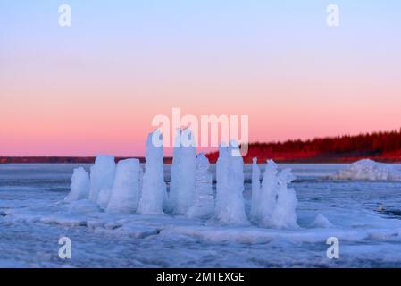 Un panorama de hielo cortado arrojado y derretido con pilares para descongelar y comer se coloca en el río Vilyui en Yakutia en una brillante puesta de sol Foto de stock