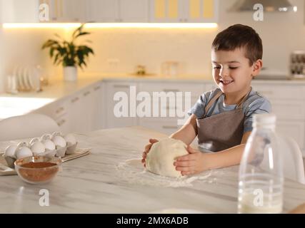 Lindo niño pequeño con masa en la mesa en la cocina. Cocinar pastelería Foto de stock