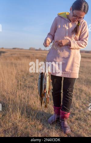 Yakut joven pescador sosteniendo una gran cantidad de peces púas atrapadas colgando de Fish Stringer en el campo. Foto de stock