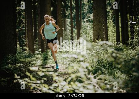 Triatleta profesional en una vuelta de entrenamiento de trail running en el bosque cerca de Kaufbeuren, Allgäu, Baviera, Alemania Foto de stock
