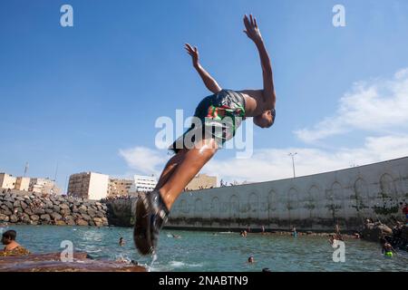 En Casablanca, Marruecos, un adolescente se sumerge en una piscina natural formada por el muro rompeolas de la ciudad; Casablanca, Marruecos Foto de stock