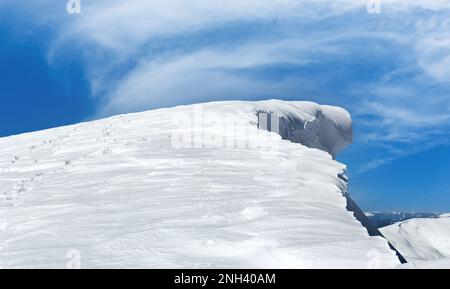 Cima de montaña de invierno con gorro de nieve con diseño de hada y huella humana en las laderas nevadas de la montaña. Foto de stock