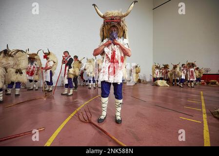 NOTA DEL EDITOR: La imagen contiene contenido gráfico) Una habitación llena  de Momotxorros, personajes que son mitad hombre y mitad toro. Llevan ropa  manchada de sangre de carnero y llevan grandes cuernos