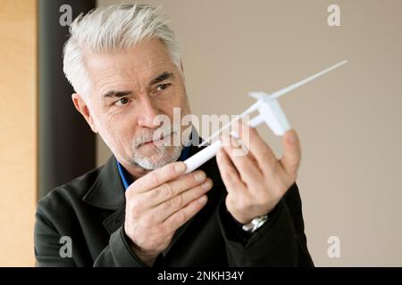 Hombre de negocios examinando el modelo de turbina de viento en la oficina Foto de stock