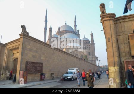 El Cairo, Egipto - 7 de enero de 2016: En un día de invierno, los visitantes salen de las puertas de la Ciudadela de Saladino con la mezquita Muhammad Ali y el museo militar en la parte posterior Foto de stock