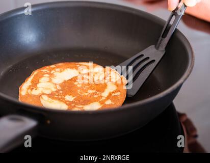 Foto horizontal del foco principal en el pancake está volteada en sartén  caliente en la parte superior de la estufa de gas gama Fotografía de stock  - Alamy