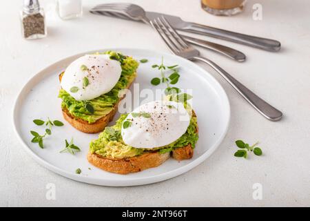 Tostadas de masa madre con puré de aguacate y huevos escalfados con hierbas, idea de desayuno saludable Foto de stock