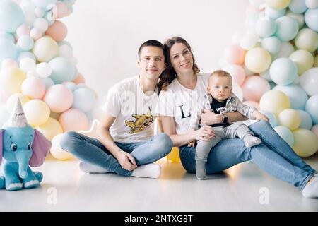 Familia joven feliz celebra el primer cumpleaños del niño el bebé tiene 1  año el concepto de una fiesta infantil con globos