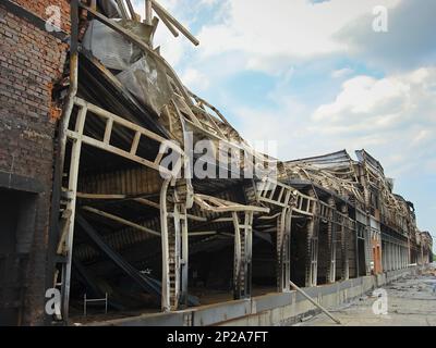 Un almacén con una rampa de carga después de un incendio. Estructura metálica quemada del edificio. Consecuencias del incendio. Foto de stock