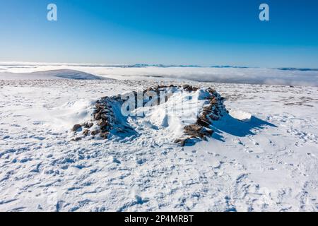 El refugio cairn en el camino a la cima de la montaña escocesa Munro de Sgor Gaoith en invierno. Foto de stock