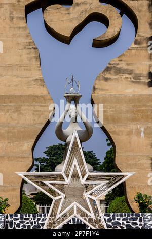 vista de cerca desde delante del monumento de la independencia en lomé togo de la silueta humana en monumento de piedra con cinco puntos de estrella frente y estatua detrás Foto de stock