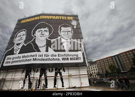 Ein Plakat vonder Hungerlohnpartei.de mit FDP Bundesvorsitzender Guido Westerwelle, links, Bundeskanzlerin Angela Merkel und Bundeswirtschaftsminister Karl-Theodor zu Guttenberg, rechts, steht am Samstag, Sept. 12, 2009 in Berlin. (AP Photo/Maya Hitij)--- A poster of the 'pittance party' showing Guido Westerwelle, leader of the Free Democratic Party (FDP), left, German Chancellor Angela Merkel (CDU) and German Economy Minister Karl-Theodor zu Guttenberg (CDU), right, is seen on a building in Berlin, Saturday, Sept. 12, 2009. The general election in Germany will be held on Sept. 27, 2009. The b
