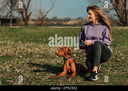 Mujer y perro sentado en el suelo en el parque Foto de stock