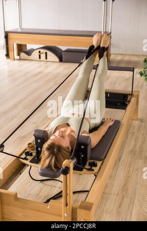 Mujer entrenando pilates en la cama reformer máquina de estudio de pilates  reformer para ejercicios de fitness en g