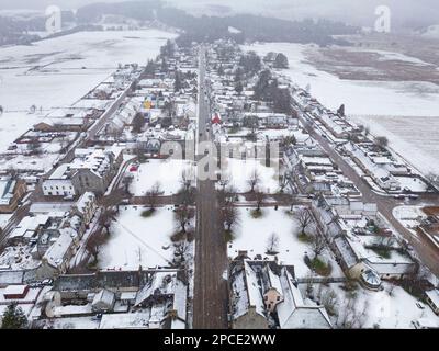Tomintoul, Moray, Escocia, Reino Unido. 13 de marzo de 2023. Vista aérea de la plaza del pueblo en Tomintoul en Moray cubierto de nieve. Se espera que Escocia vea heav Foto de stock