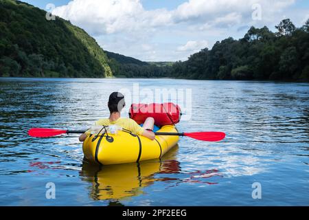 Turista en barco de goma de packraft amarillo con el padle rojo en un río del amanecer. Rafting. Concepto vital activo Foto de stock