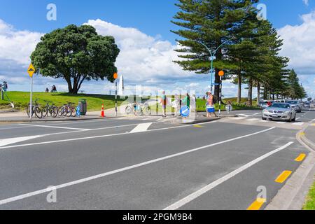 Tauranga Nueva Zelanda - Marzo 22 2023: Grupo familiar con papelera y tablas de boogie cruzan la calle para ir a Main Beach en Mount Maunganui. Foto de stock