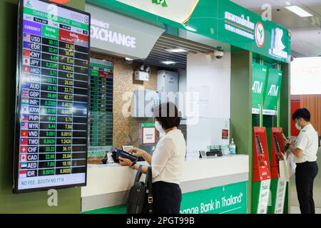 Bangkok, Tailandia - 1 de febrero de 2023: Viajero de negocios asiático en el mostrador de cambio de moneda del aeropuerto de suvarnabhumi con cambio de moneda Foto de stock