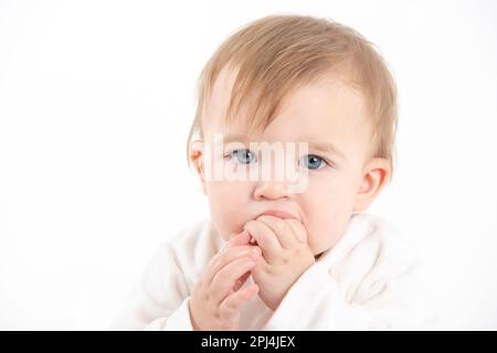 Stock Foto de estudio con el fondo blanco de un rostro del bebé con los dedos en la boca Foto de stock