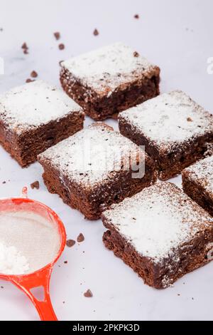 Los trozos cuadrados recién horneados de brownie de chocolate espolvoreados con azúcar en polvo Foto de stock