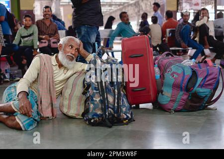 Un anciano musulmán barbudo que se relaja junto a su equipaje mientras espera un tren en Chhatrapati Shivaji Maharaj Terminus en Mumbai, India Foto de stock