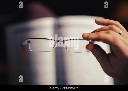 Gafas en una mano femenina. El concepto de mala vista, lectura de libros, aprendizaje. Foto de stock