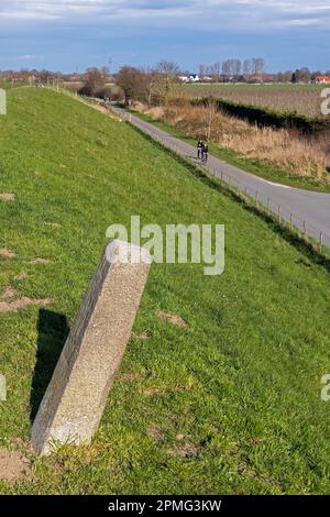 Piedra fronteriza entre Haselau y Moorrege, dique, carril bici, ciclistas, Schleswig-Holstein, Alemania Foto de stock