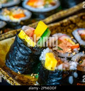 Gimbap es un plato coreano hecho de arroz cocido e ingredientes como verduras, pescado y carnes que se enrollan en gim (hojas secas de algas marinas) y. Foto de stock