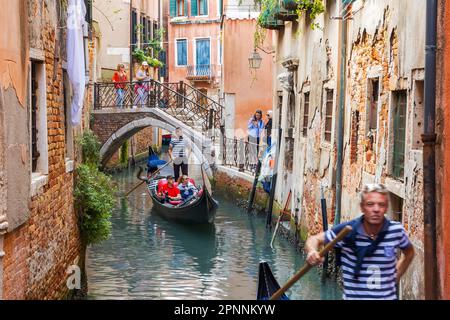 Gondoleros en góndolas tradicionales, visitas turísticas para turistas a través de canales estrechos, Venecia, Véneto, Italia Foto de stock