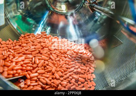 Línea automática de píldoras de medicina de cápsulas en fábrica farmacéutica, las drogas se mueven con el uso de equipos rotativos en taller de planta química. Foto de stock