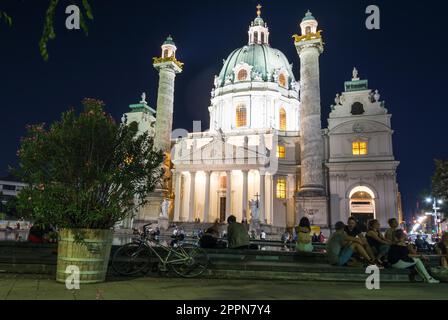 VIENNA, AUSTRIA - AUGUST 30: Tourists at the illuminated Baroque Karlskirche in Vienna, Austria on August 30, 2017. The church is considered the most Stock Photo
