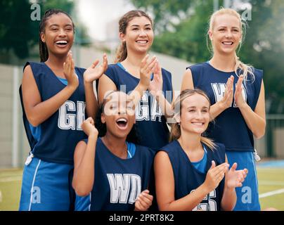 Netball, deportes y aplausos con un equipo femenino en celebración de una victoria como ganadora en un campo al aire libre. Fitness, salud y trabajo en equipo con una mujer Foto de stock