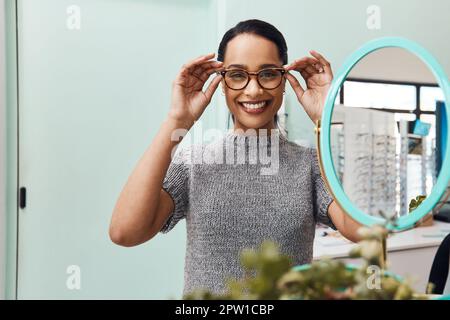 Mujer que lleva un par de gafas de moda, gafas elegantes y nuevas lentes de prescripción en un optometrista. Retrato de un cliente que elige, compra y sh Foto de stock