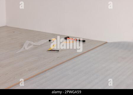 Herramientas de reparación y tablones de parquet en el suelo en la habitación preparados para la renovación Foto de stock