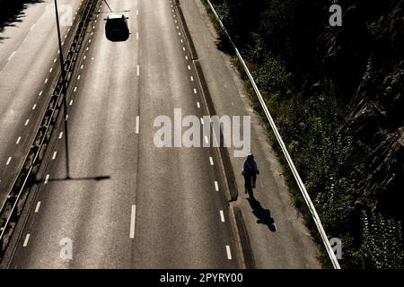 Gotemburgo, Suecia - 01 2022 de agosto: Ciclista solitario en una carretera para bicicletas por una autopista. Foto de stock