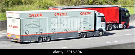 El remolque de transporte de entrega de vehículos cerrados Cazoo y el camión de camión hgv adelantan a otro vehículo comercial que conduce por la carretera de la autopista M25, Inglaterra, Reino Unido Foto de stock